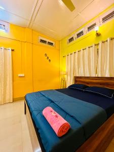 a bedroom with a blue bed with yellow walls at Bloom homestay in Guwahati