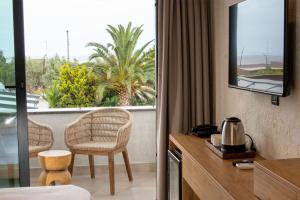 a room with a balcony with a chair and a window at Club Kavala Beach Hotel Assos in Behramkale