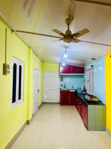 a kitchen with red and yellow walls and a ceiling fan at Bloom homestay in Guwahati
