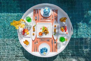 a plate of food on a table next to a pool at Sunsuri Phuket - SHA Plus in Nai Harn Beach