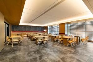 a dining room with wooden tables and chairs at Floral Hotel Banlan Cangzhou Convention and Exhibition Center High-speed Railway West Station in Zhifangtou