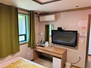 - une chambre avec un bureau et une télévision murale dans l'établissement J Motel, à Boryeong