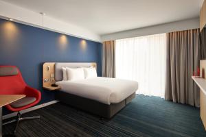 a hotel room with a bed and a red chair at Holiday Inn Express London Limehouse by IHG in London +70 photos