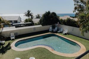 a swimming pool in a yard with chairs and a fence at Pandanus Palms Ocean View Holiday Resort on Point Lookout in Point Lookout