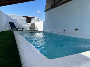 a swimming pool on the side of a building with two chairs at Casacastillo28 in Peñarroya de Tastavins