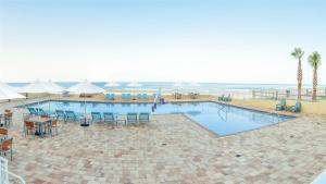 a large swimming pool with tables and chairs next to the ocean at Hyatt Place Daytona Beach-Oceanfront in Daytona Beach