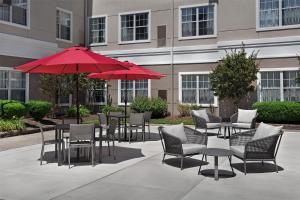 克兰福德Homewood Suites by Hilton Newark-Cranford的一个带桌椅和红色遮阳伞的庭院