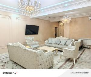 a living room with couches and a table and chandeliers at Cozy Stay in Dushanbe