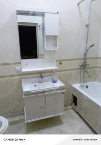 a white bathroom with a sink and a mirror at Cozy Stay in Dushanbe