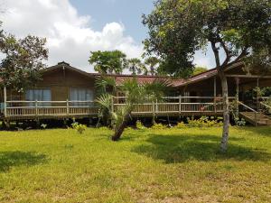 a wooden house with a porch and a yard at Cliffside Amani Wooden Villa with Stunning Ocean Views for an Authentic Tanzanian Escape in Dar es Salaam