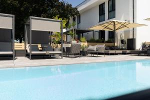 a swimming pool with chairs and an umbrella at Kracher Hotel Doppelzimmer - für maximal 4 Personen inklusive Pool in Illmitz