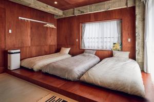 two beds in a room with wooden walls at Koubanoyado in Tokyo