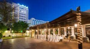 a restaurant with white tables and chairs in front of a building at Al Falaj Hotel in Muscat