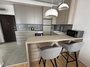 a kitchen with a counter with two chairs and a sink at City Center Apartment in Zrenjanin +6 photos