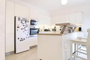 a white kitchen with a refrigerator with magnets on it at Luxusný rodinný dom v Trenčíne in Trenčín