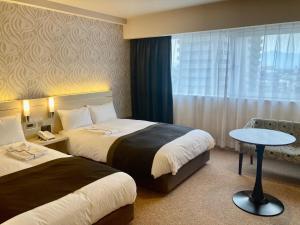 ein Hotelzimmer mit zwei Betten und einem Tisch in der Unterkunft Kusatsu Estopia Hotel in Kusatsu