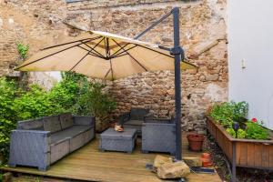 Un patio con una sombrilla y un sofá y sillas. en Le Duplex entre terre et mer, en Auray