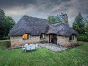 a stone house with a table and chairs in front of it at Ambleside Cottage in Underberg