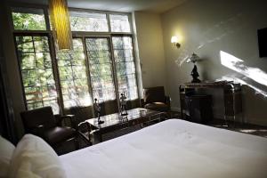a bedroom with a bed and a desk and windows at Demeures & Châteaux La Belle Meuniere in Royat +36 photos