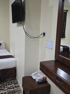 a room with a bed and a television and a table at فندق ليمه التاج in Az Zahrāʼ