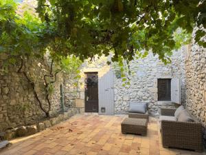 a stone building with two chairs and a door at Maison Casamande & SPA - Luxe et sérénité dans un domaine d'amandiers in Bouquet