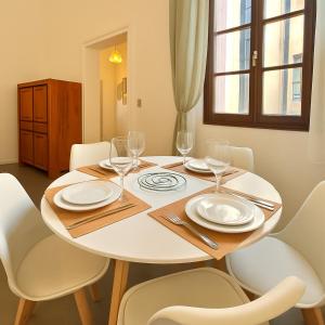 a table with white plates and glasses on it at Le Logis du Château , Charme au cœur de Sommières in Sommières +18 photos