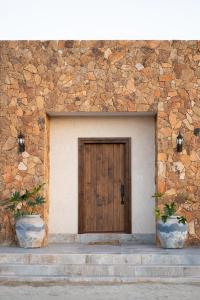 a wooden door in a stone building with two pots at Baja Toscana in Valle de Guadalupe