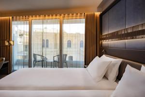 a bedroom with a large bed and a balcony at Hyatt Regency Malta in St. Julianʼs