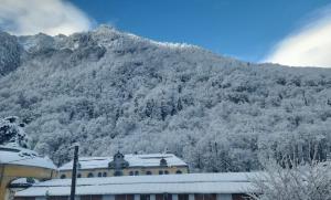 een berg bedekt met sneeuw met een gebouw voor de deur bij Centre ville Appartement 4 personnes in Cauterets