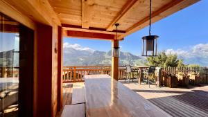 una terrazza in legno con tavolo e vista sulle montagne di Chalet Lambersens Serbijanka a Manigod