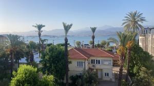a view of a house and palm trees and the water at Modern Flat Walk to Shops, Cafes Harbour in Fethiye