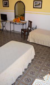 una camera d'albergo con due letti e uno specchio di B&B Le Coccinelle a Santo Stefano di Camastra