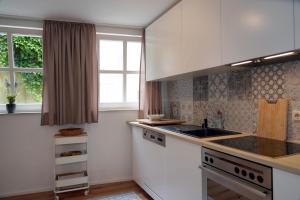 a kitchen with white cabinets and a sink and a window at Eifel Fewo in Neuerburg
