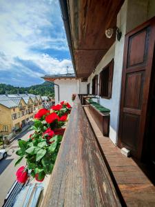 - un balcon avec des fleurs rouges dans un bâtiment dans l'établissement Rium Mare & Monti, à Pieve di Cadore