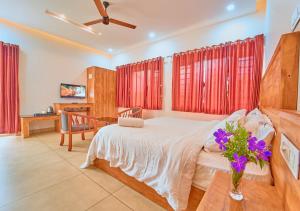 a bedroom with a bed with a vase of flowers on a table at Ice Pellets Munnar Resort with Pool by VOYE HOMES in Munnar
