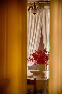 un tavolo con un vaso di fiori e una finestra di B&B Le Coccinelle a Santo Stefano di Camastra
