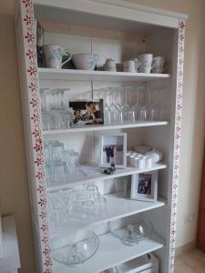 a white shelf filled with glass dishes and cups at evvIVA's house in Osimo +8 photos