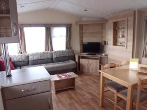 eine Küche und ein Wohnzimmer mit einem Sofa und einem Tisch in der Unterkunft Camping Ter Hoeve in Bredene