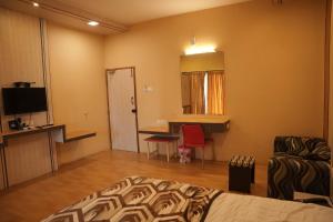 a bedroom with a bed and a desk and a mirror at Hotel Gala Estancia in Yercaud