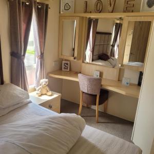 a bedroom with a bed and a desk and mirror at 125 Maple Lake Southview Caravan Park in Winthorpe