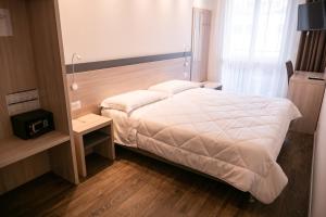 a bedroom with a white bed and a night stand at Hotel Elys in Pieve Emanuele