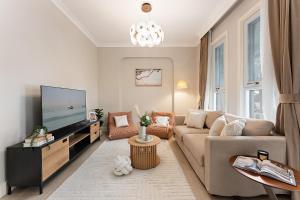 een woonkamer met een bank en een flatscreen-tv bij Trendy 4BR Petersham Stay Steps from Top Cafés in Sydney