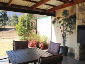 un tavolo e sedie di legno su un patio di Muirfield Cottages a Clarens