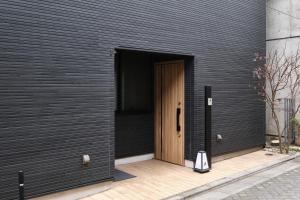 a black wall with a wooden door with a bag in it at Asagaya House by Tranova in Tokyo +40 photos