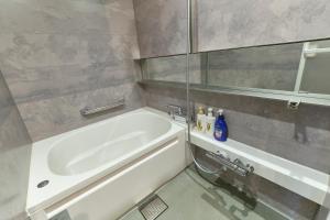 a bathroom with a white tub and a sink at Asagaya House by Tranova in Tokyo