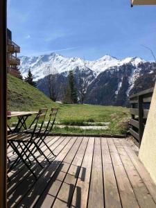 una terraza de madera con mesa de picnic y montañas cubiertas de nieve en Le Parc03, en Peisey-Nancroix