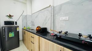 a kitchen with a black counter top and a refrigerator at Olive Serviced Apartments - HICC Hitex Hyderabad in Hyderabad