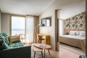 a hotel room with a bed and a couch at ALEGRIA El Mar & Spa 4 SUP in Santa Susanna