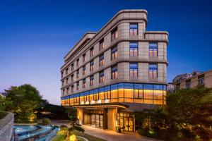 上海上海虹桥荷逸唐酒店北新泾地铁站Shanghai Hongqiao Heyitang Hotel Beixinjing Subway Station Branch的一座灰色的高楼，前面有一个池塘
