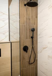 La salle de bains est pourvue d'une douche et d'une porte en bois. dans l'établissement Chic 1BR Flat & Garage I Garden Residence, Varna by Flat Mаnаger, à Varna